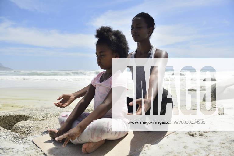 Mother with daughter doing a yoga exercise on the beach model released Symbolfoto ECPF00395