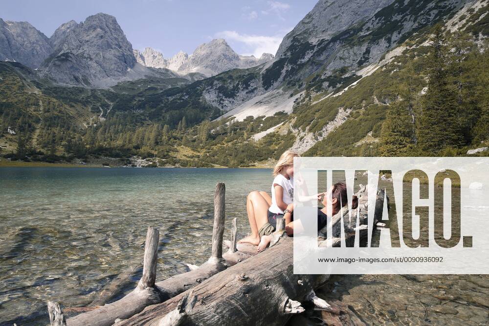 Austria, Tyrol, playful mother and daughter on tree trunk at lake Seebensee model released Symbolfoto FKF03289