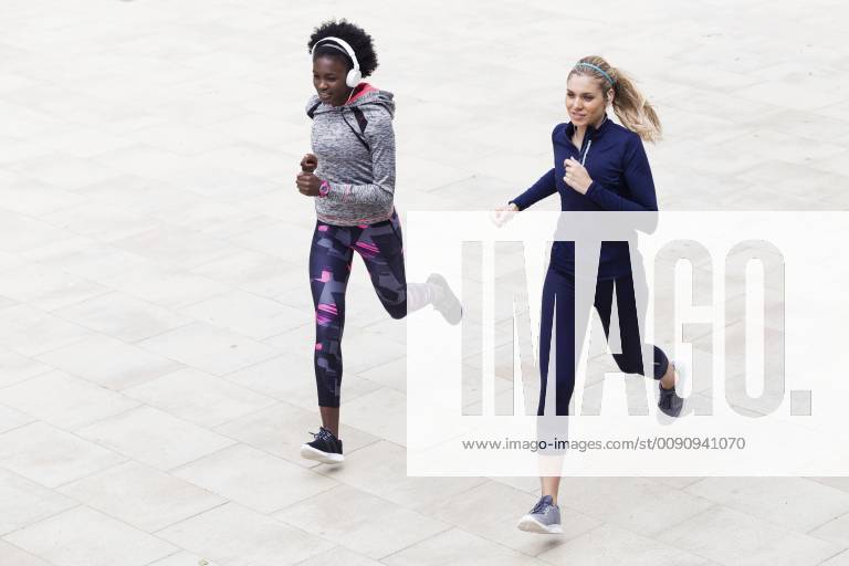 Two sporty young women running together in the city model released Symbolfoto JSRF00118