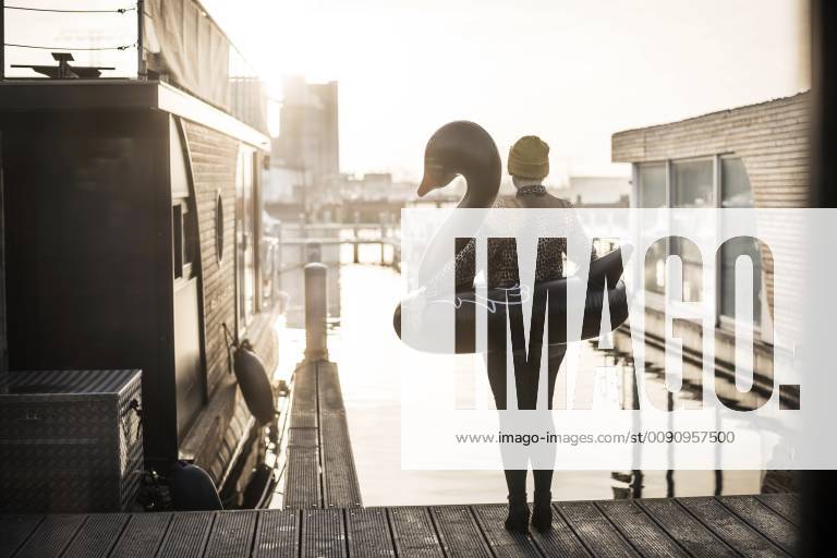 Businesswoman with floating swan standing on a houseboat, looking at distance model released Symbolfoto property released MJRF00085