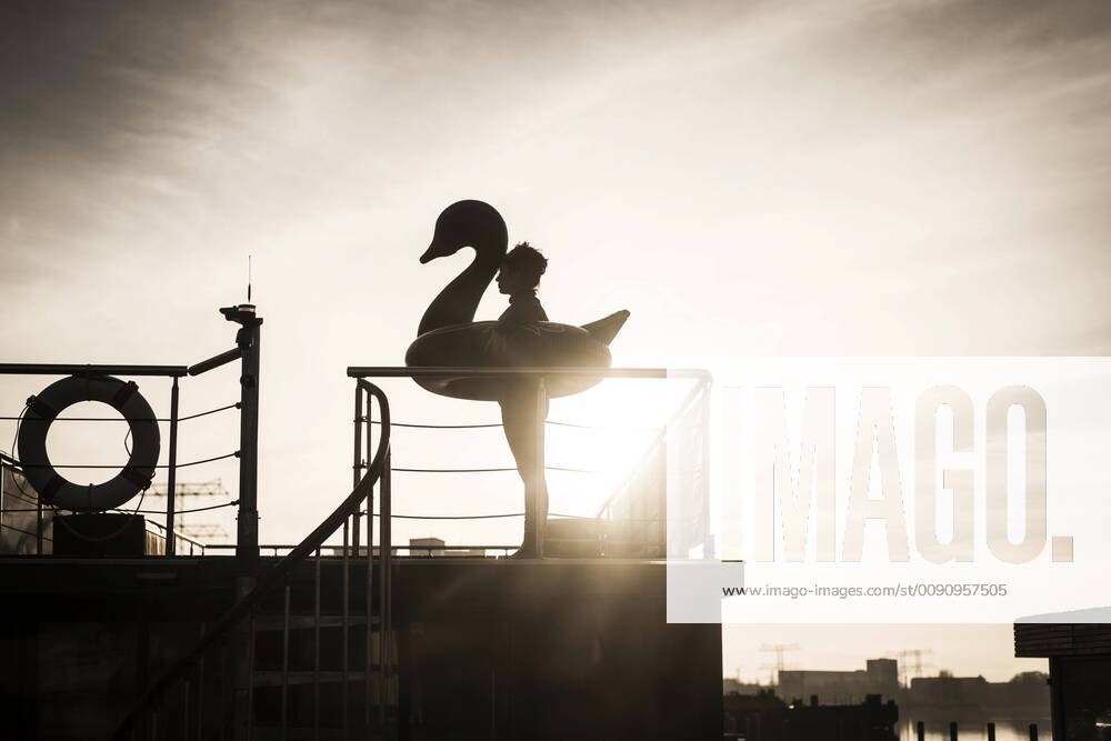 Businesswoman with floating swan standing on a houseboat, looking at distance model released Symbolfoto property released MJRF00090