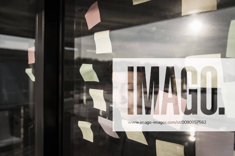 Tired woman leaning against window pane with sticky notes model released Symbolfoto property released MJRF00107
