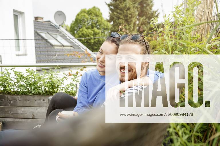 Young couple relaxing on their balcony, sitting on couch model released Symbolfoto property released PESF01161
