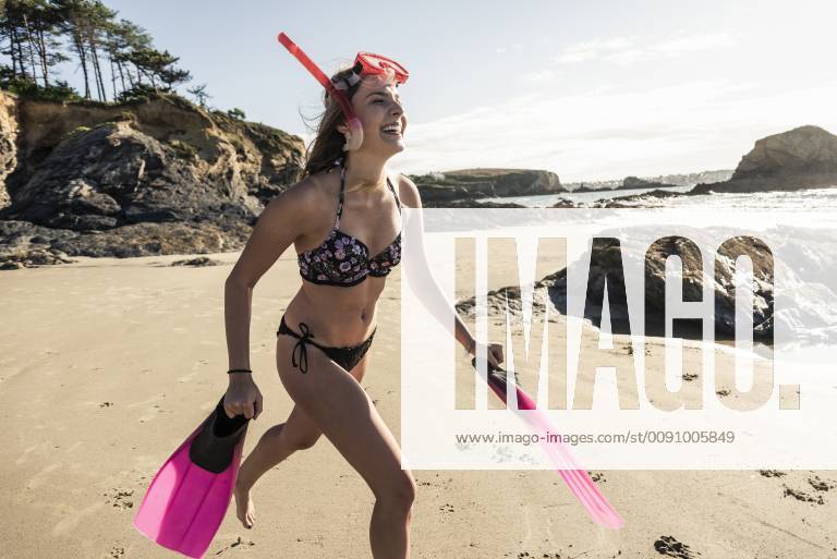 Happy young woman with snorkelling equipment, running on the beach model released Symbolfoto UUF16491