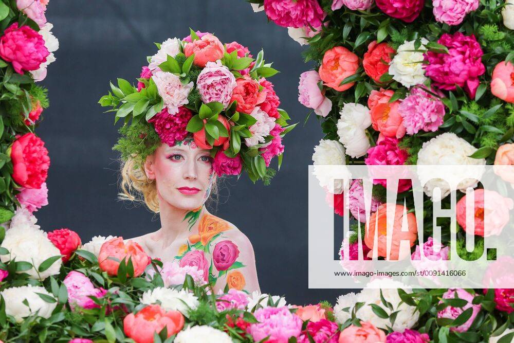 London, UK, UK - London, UK. A model wearing a floral display hat and body art poses for photographers at the Primrose Hill stand. .