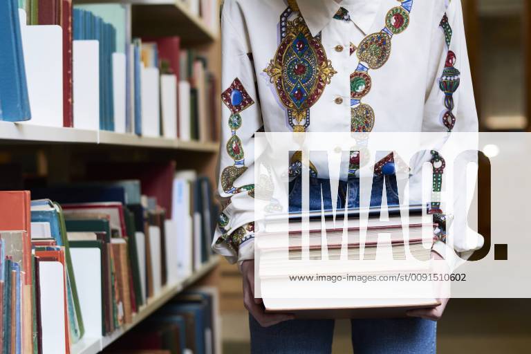 Female student with books in a public library model released Symbolfoto IGGF01057