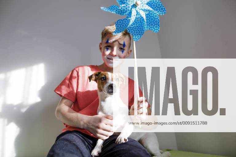 Portrait of Jack Russel Terrier with boy made up as a clown holding pin wheel model released Symbolfoto property released KMKF00780