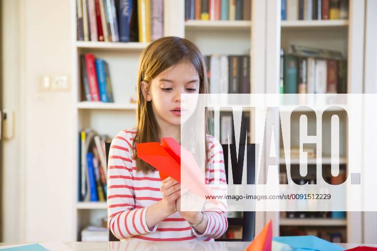 Girl tinkering paper plane on table at home model released Symbolfoto property released LVF06860