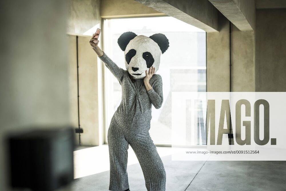 Woman with panda mask standing in office, taking selfie model released Symbolfoto property released MJRF00180