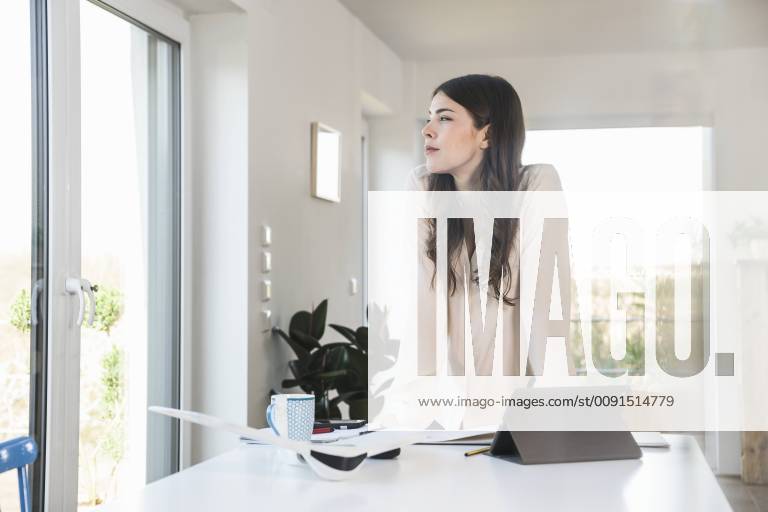 Young woman standing at table at home looking sideways model released Symbolfoto property released UUF16951