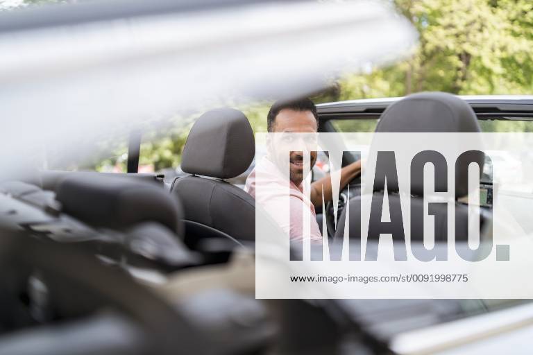 Man sitting in car with closing convertible top model released Symbolfoto DIGF06988