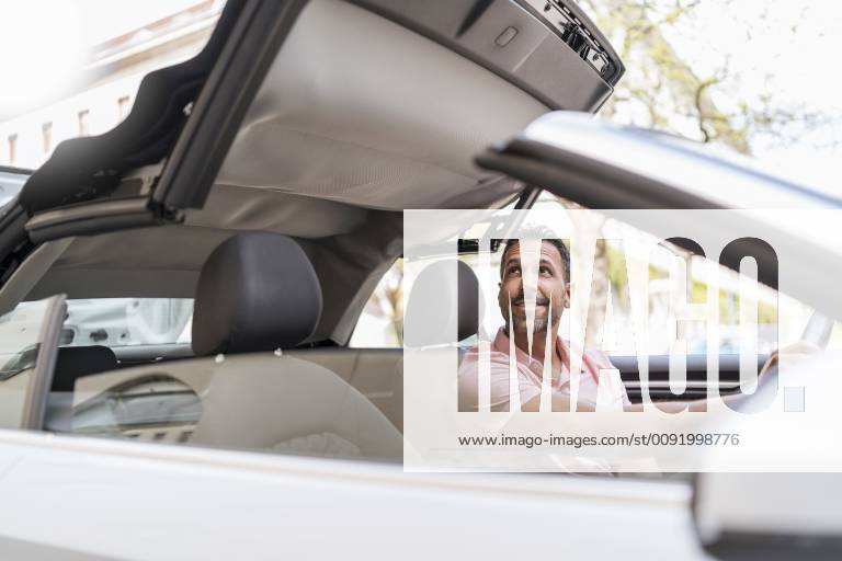Man sitting in car with closing convertible top model released Symbolfoto DIGF06990