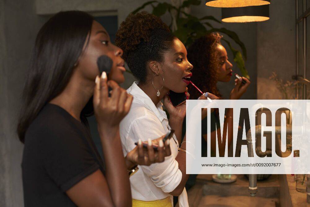 Three friends applying makeup at ladies room model released Symbolfoto property released VEGF00147