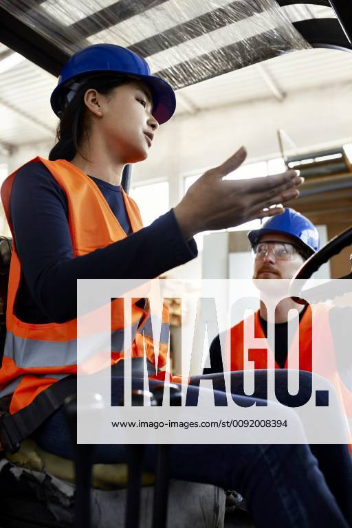 Man talking to female worker on forklift in factory model released Symbolfoto property released ZEDF02156