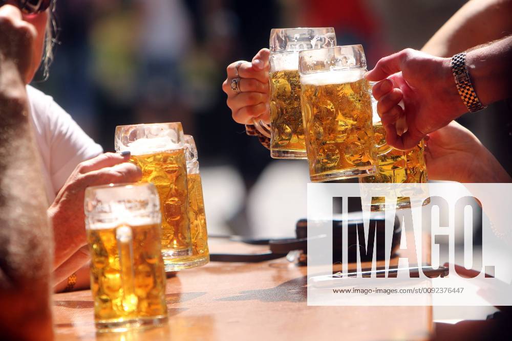 Gemeinsames Zuprosten mit Maßkrüge n Bier im Biergarten am Viktualienmarkt in München, Bayern, Deutschland