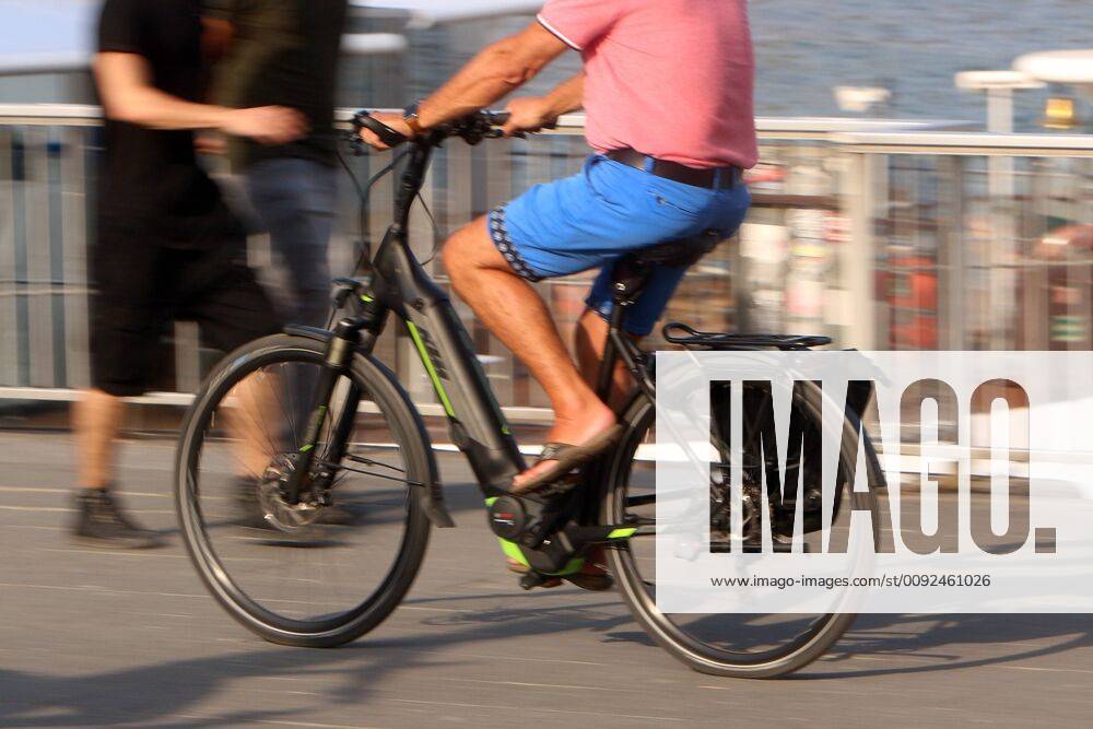 Mann fährt mit einem Elektrofahrrad auf der Uferpromenade am Rhein in der Innenstadt von Köln, Nordrhein Westfalen, Deutschland