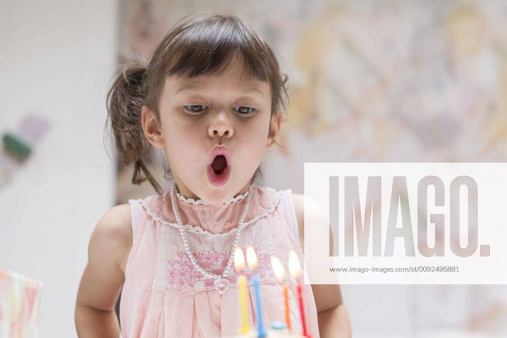 Portrait of little girl blowing out burning candles on her birthday cake model released Symbolfoto DRF01741