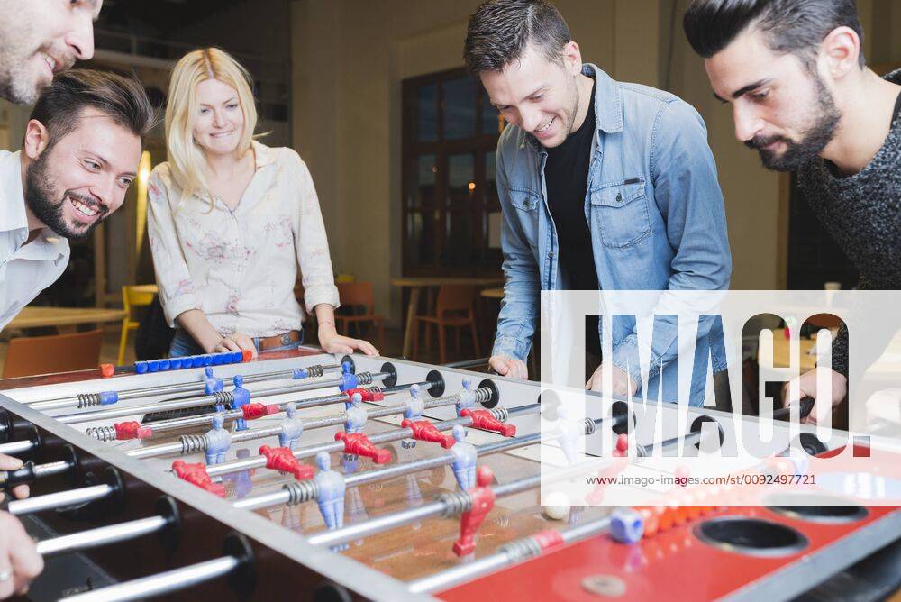 Happy colleagues playing foosball in office model released Symbolfoto property released FMOF00685