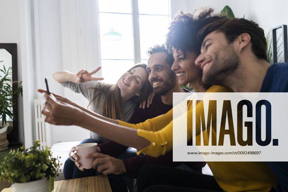 Four happy friends sitting on couch taking a selfie model released Symbolfoto property released GIOF06441