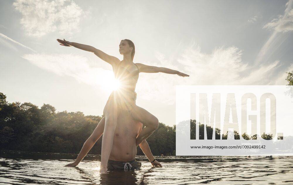 Young woman sitting on shoulders of young man standing in lake, enjoying the sun model released Symbolfoto GUSF02308