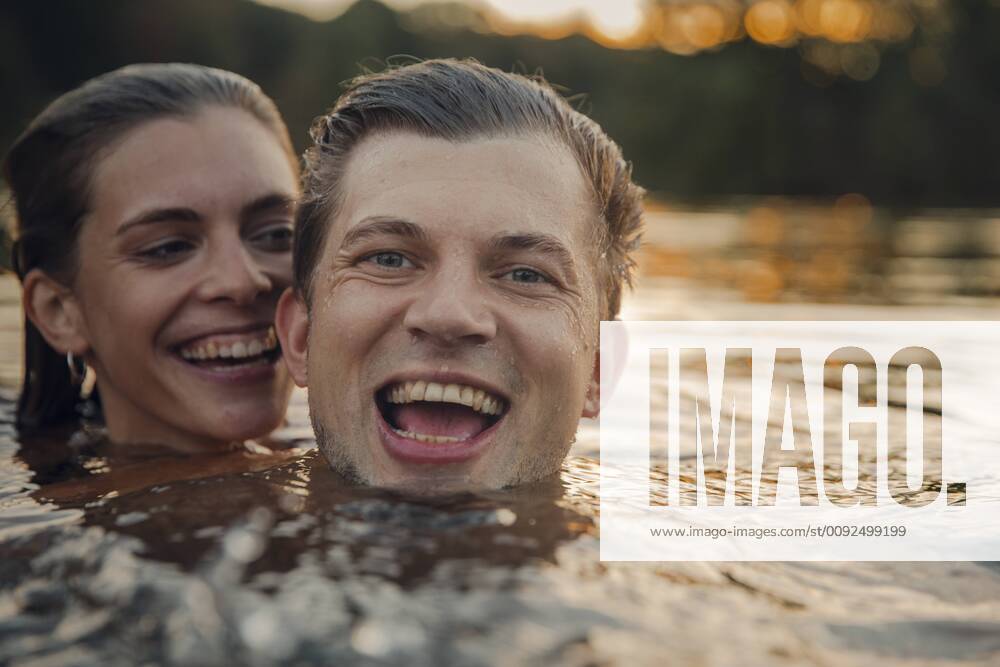Young couple swimming in lake at sunset model released Symbolfoto GUSF02365