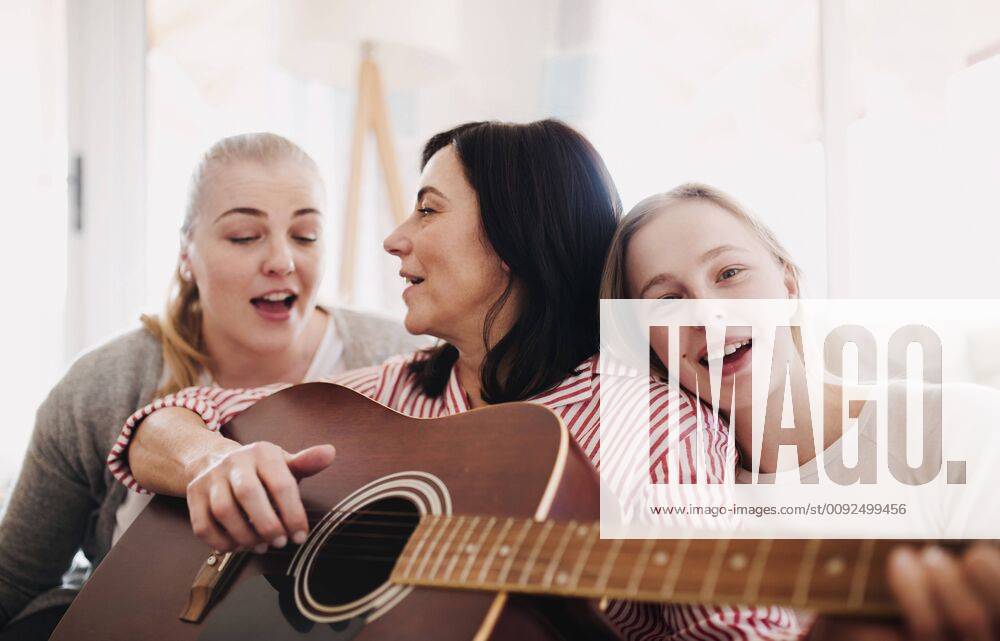 IMAGO Creative: Digitale Welt, Verzicht auf Technologie Mature woman with two daughters singing and playing guitar at home model released Symbolfoto property released HAPF02963