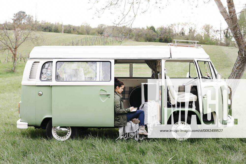 Young woman sitting in her camper, writing in a notebook model released Symbolfoto property released HMEF00442
