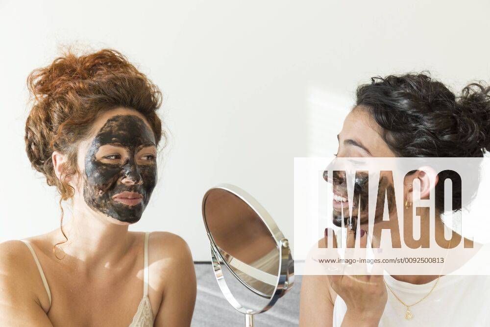 Two happy young women applying facial masks at home model released Symbolfoto property released JPTF00240