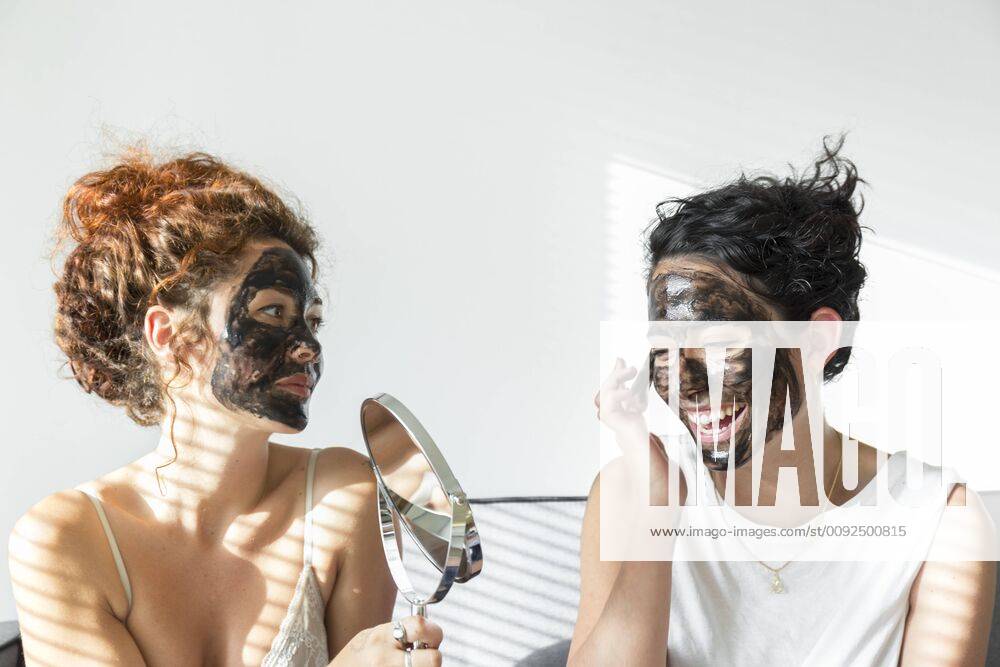 Two happy young women applying facial masks at home model released Symbolfoto property released JPTF00242