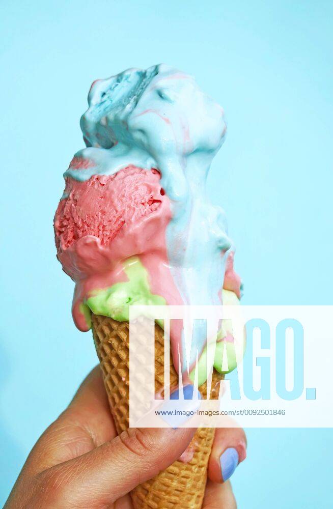Woman s hand holding ice-cream cone with melting icecream in front of blue background model released Symbolfoto JTF01251