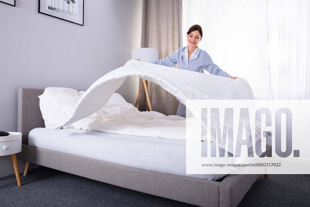 Housekeeper Arranging Bedsheet On Bed ,model released, Symbolfoto