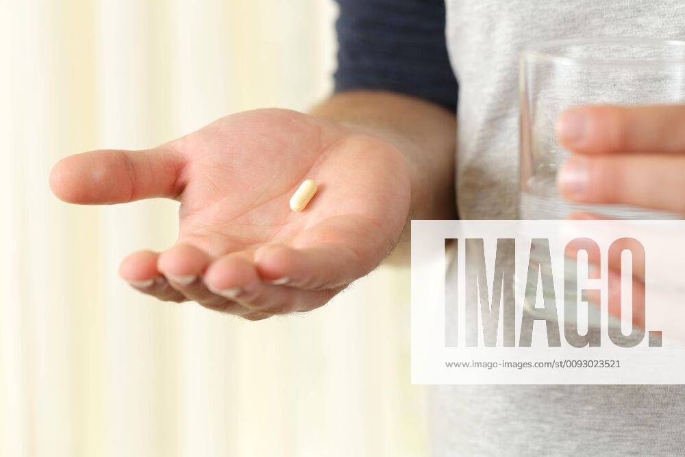 Man hand showing a pill and a glass of water ,model released, Symbolfoto