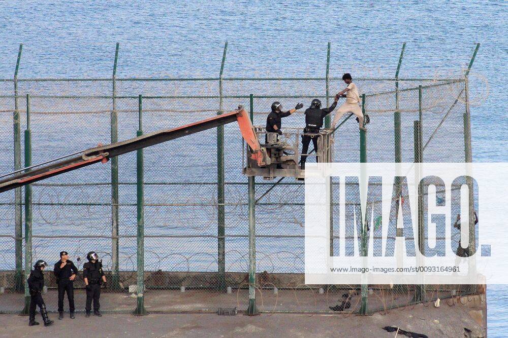 A migrant is detained by the police on a crane as he remained on top of the border fence on the wait to safely jump onto Spanish soil in Ceuta, Spanish enclave in the north of Africa, 30 August 2019. Over 150 migrants managed to enter in Spain from Morocco, in a mass breach of the border fence, in early morning. Over 150 migrants jump the fence in Ceuta !ACHTUNG: NUR REDAKTIONELLE NUTZUNG!