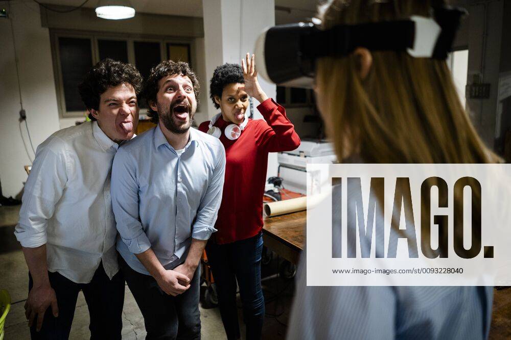 IMAGO Creative, Lifestyle, Gaming Playful colleagues looking at woman wearing VR glasses in office model released Symbolfoto property released GIOF06847