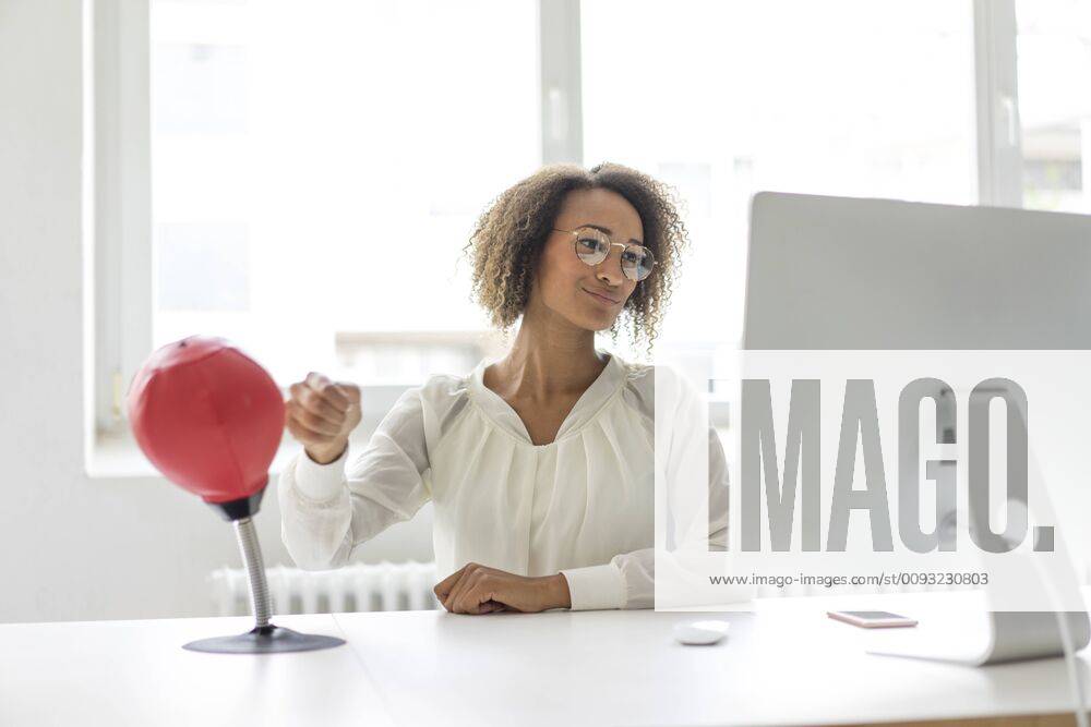 Portrait of young freelancer sitting at desk in office boxing punching ball while looking at computer model released Symbolfoto property released MOEF02318
