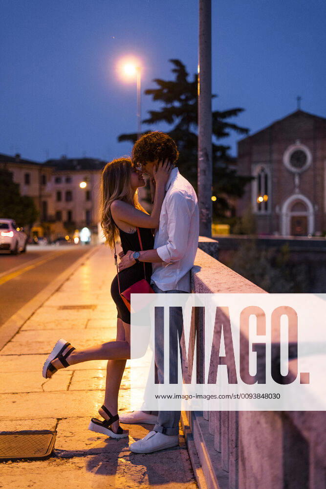 Affectionate young couple kissing inon a bridge at night, Verona, Italy model released Symbolfoto GIOF07023