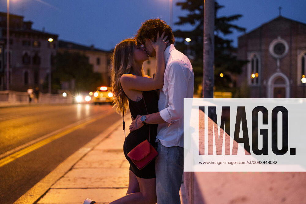 Affectionate young couple kissing inon a bridge at night, Verona, Italy model released Symbolfoto GIOF07026