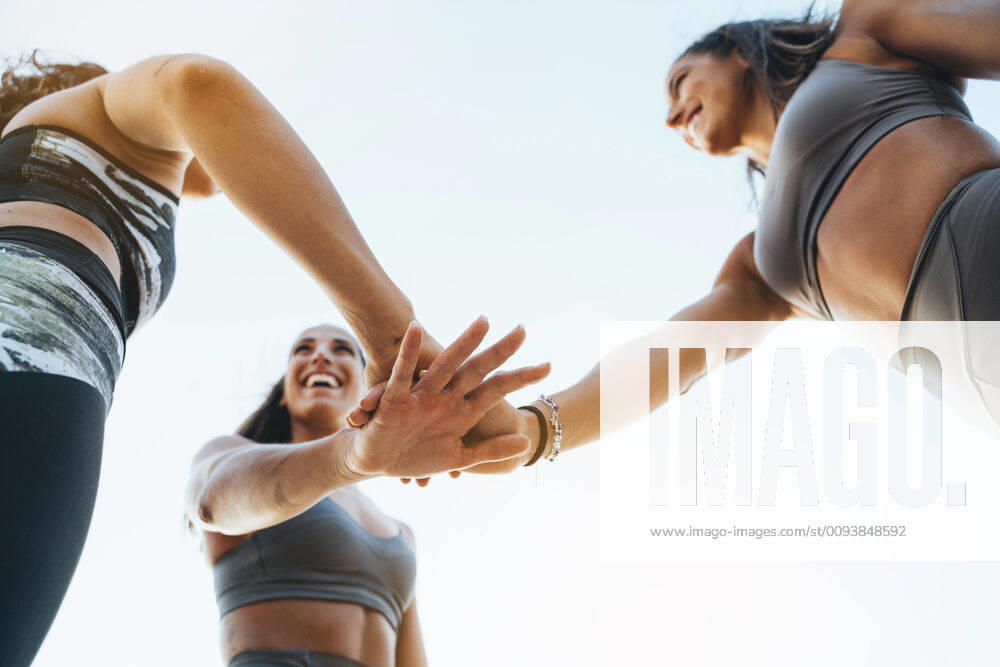 Three happy sporty women stacking their hands after doing sports model released Symbolfoto JCMF00204