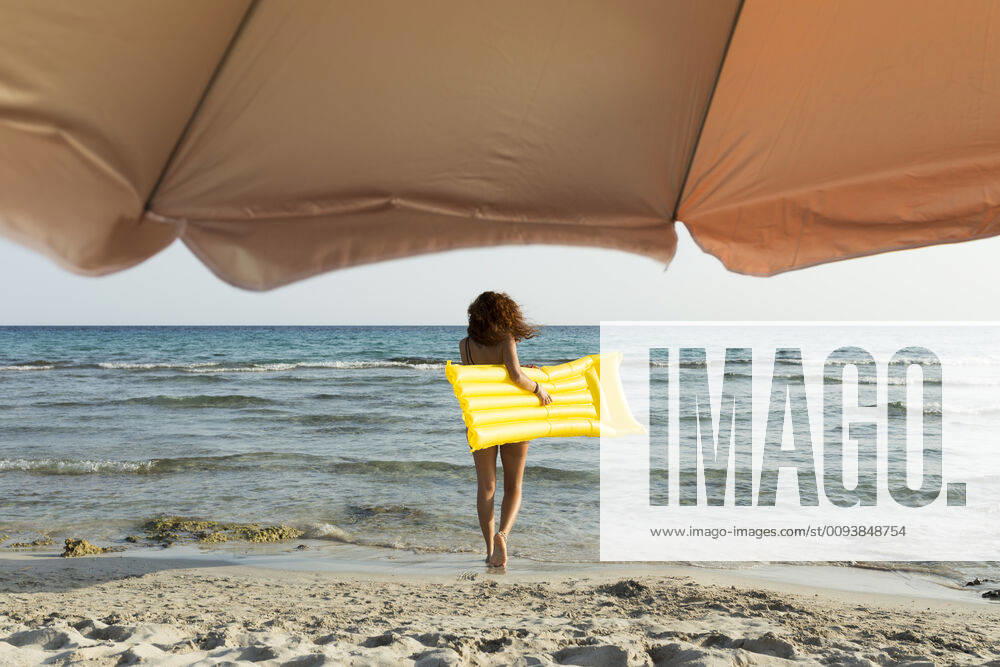 Young woman with yellow airbed at the beach model released Symbolfoto JPTF00257