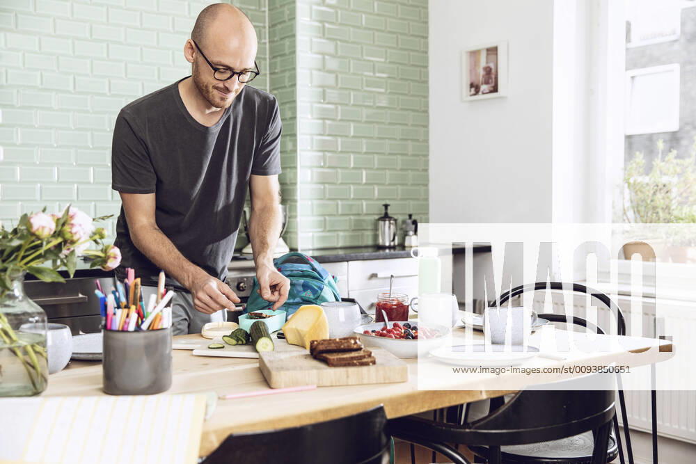 IMAGO Creative: Gesellschaft, Schule, Schulanfang Man in a kitchen packing snacks for lunch break model released Symbolfoto property released MCF00280