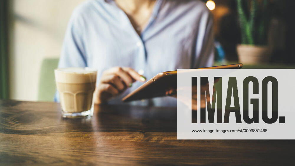 Woman sitting in a cafe using a digital tablet and drinking a coffee model released Symbolfoto OYF00055