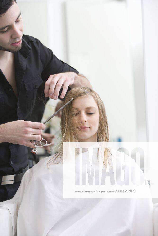 Man cutting a young womans hair in the hairdressers,model released, Symbolfoto,property released 03B99845