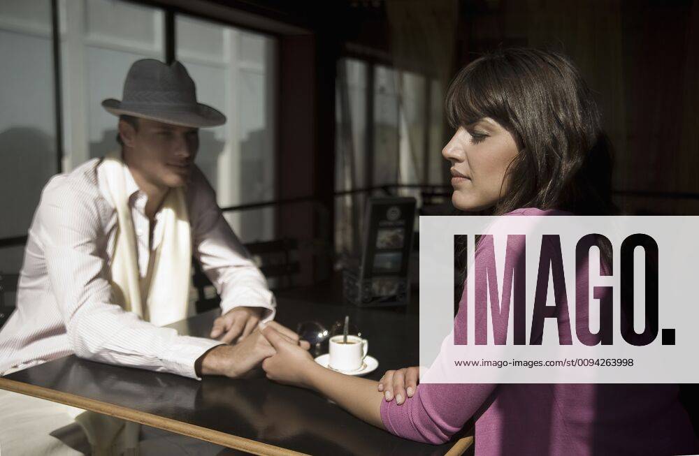 Young couple sit holding hands in cafe,model released, Symbolfoto 03C04918