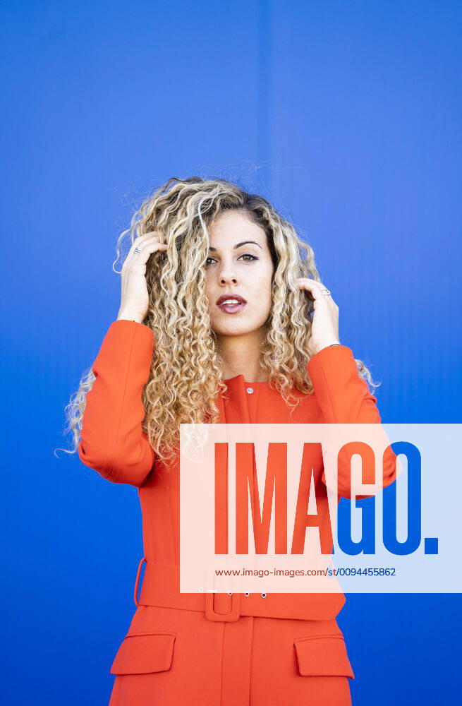 Portrait of young woman wearing red dress in front of blue background model released Symbolfoto DAMF00148