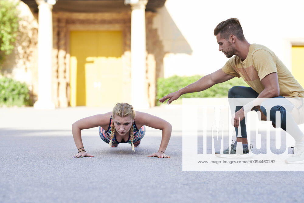 Fitness coach practicing with young woman outdoors in the city model released Symbolfoto JNDF00091