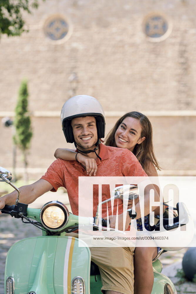 IMAGO Creative, Jahreszeit Sommer, Sommer in der Stadt Portrait of a smiling young couple on a vintage motor scooter model released Symbolfoto JNDF00124