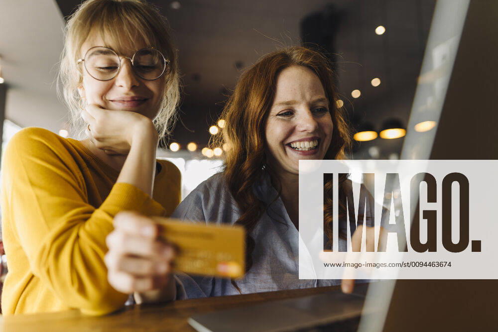 Two happy female friends with laptop and credit card in a cafe model released Symbolfoto property released KNSF06709