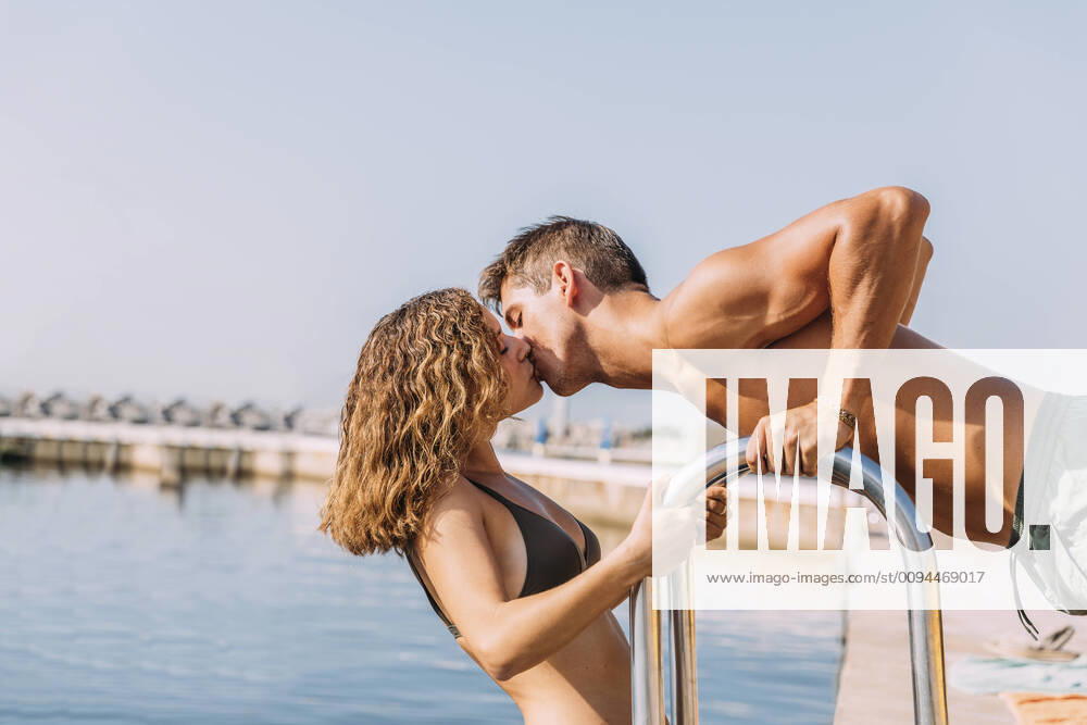 Young couple kissing on a pier at the sea model released Symbolfoto MOSF00083