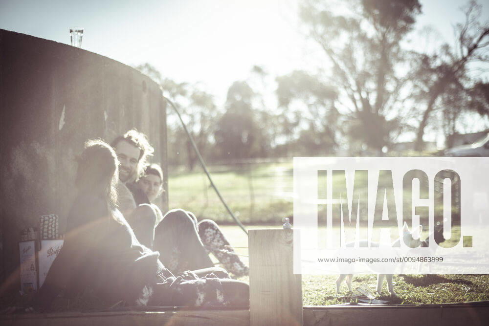 IMAGO Creative: Jahreszeit Frühling, Picknick IMAGO Creative: Landleben - Alfresco, Draußen IMAGO Creative: Landleben, Digitalisierung auf dem Land Friends with dogs sit and laugh outside in sunlight on farm Australia CR_PIDODS190930-145122-01