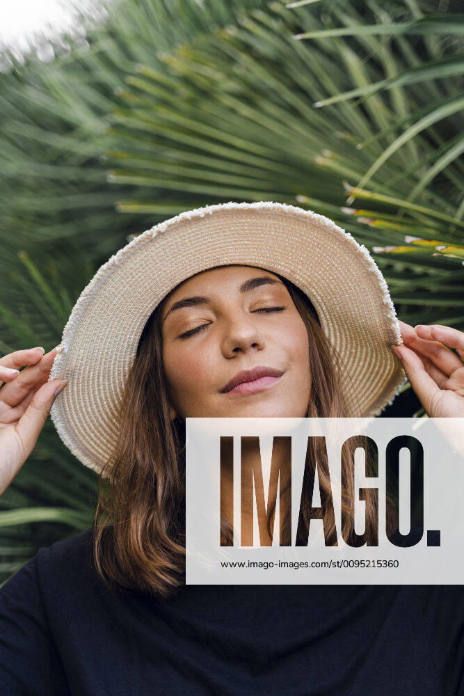 Portrait of young woman with eyes closed wearing summer hat model released Symbolfoto AFVF04173